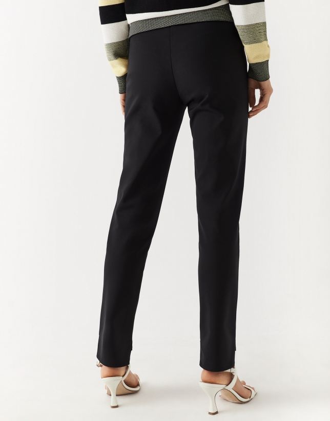 Black colored fitted pants with zippered pockets